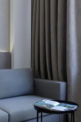 a couch with a table in front of a curtain at Philosofia Athens Suites in Athens
