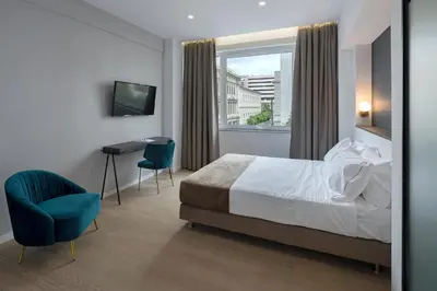 a hotel room with a bed and a desk and a window at Philosofia Athens Suites in Athens