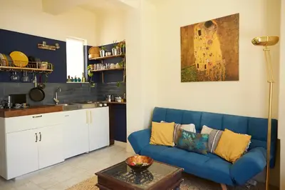 a living room with a blue couch and a kitchen at Mosaics Central aprtm with Acropolis View ! in Athens