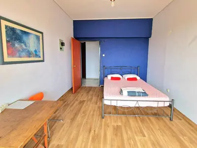a room with a bed and a table and a blue wall at SleepEasy City center in Athens