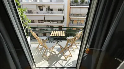 two chairs and a table on a balcony with a window at 2 Newly Renovated Charming Apartments steps from Panormou Metro Station in Athens