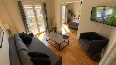 a living room with a couch and a television at 2 Newly Renovated Charming Apartments steps from Panormou Metro Station in Athens