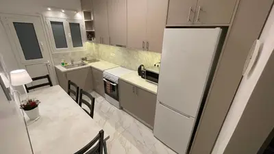 a kitchen with a white refrigerator and a table at 2 Newly Renovated Charming Apartments steps from Panormou Metro Station in Athens
