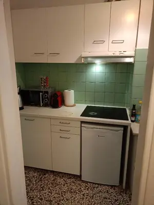 a kitchen with white cabinets and green tiles at Omonia Square Apartment in Athens