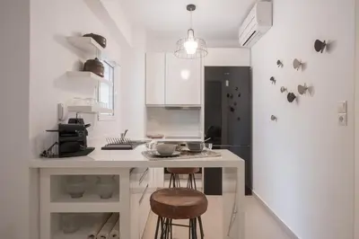 a white kitchen with a counter and stools in it at Bliss Living in Vouliagmeni