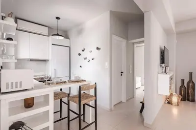 a kitchen with white cabinets and a counter with stools at Bliss Living in Vouliagmeni