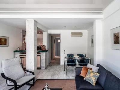 a living room with a blue couch and a kitchen at Peripatos apartment in Athens