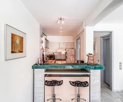a kitchen with a green counter top and two stools at Peripatos apartment in Athens