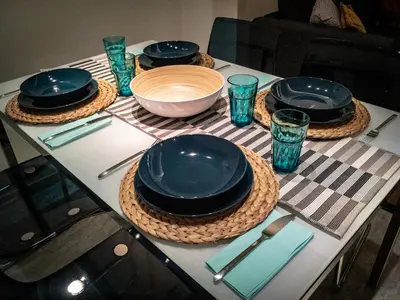 a table with plates and bowls and blue glasses at Peripatos apartment in Athens