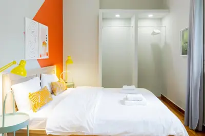 a bedroom with a large white bed with an orange wall at Acropolis Apartments in Athens