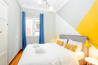 a bedroom with a white bed with blue curtains at Acropolis Apartments in Athens