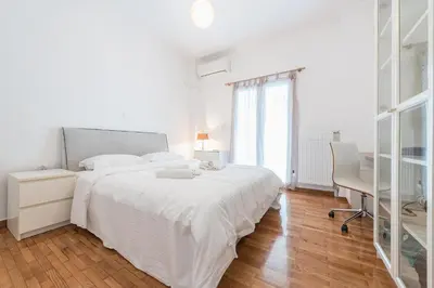 a white bedroom with a large white bed and a desk at Fresh and Clean apt for 6 in Koukaki in Athens