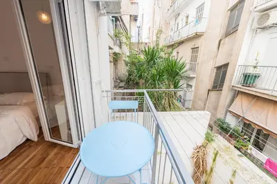 a balcony with a blue chair and a bed at Fresh and Clean apt for 6 in Koukaki in Athens