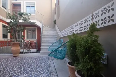 a hallway with stairs and a blue chair and plants at ATHENIAN YARD SUITES in Athens