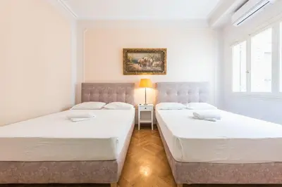 two beds in a room with white walls and windows at Athens Empire Paradise Apartment in Athens