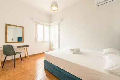 a white bedroom with a large bed and a chair at Athens Empire Paradise Apartment in Athens