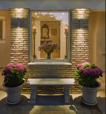 a mirror on a brick wall with a bench and flowers at Luxury 4 Bdrm Villa with Pvt Pool on the beach in Lagonissi