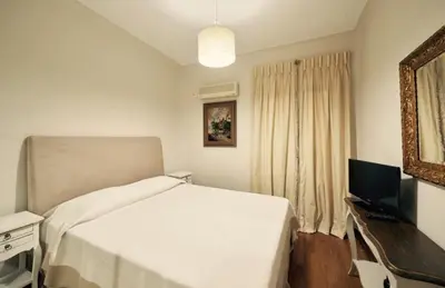 a bedroom with a white bed and a television at Luxury 4 Bdrm Villa with Pvt Pool on the beach in Lagonissi