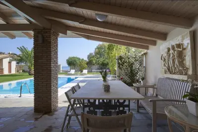 a patio with a table and chairs and a pool at Luxury 4 Bdrm Villa with Pvt Pool on the beach in Lagonissi