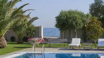 a pool with two chairs and a bench and the ocean at Luxury 4 Bdrm Villa with Pvt Pool on the beach in Lagonissi