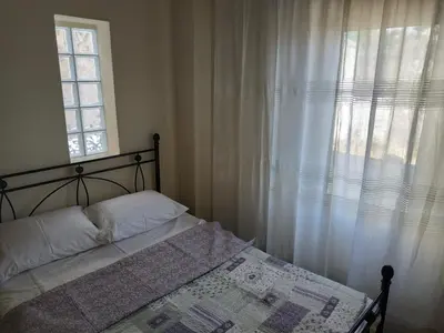 a bedroom with a bed and a window with white curtains at Near Airport And metropolitan Artemis George Cozy Home in Artemida
