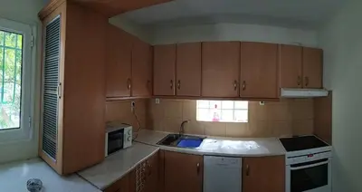 a kitchen with wooden cabinets and a sink and a microwave at Near Airport And metropolitan Artemis George Cozy Home in Artemida