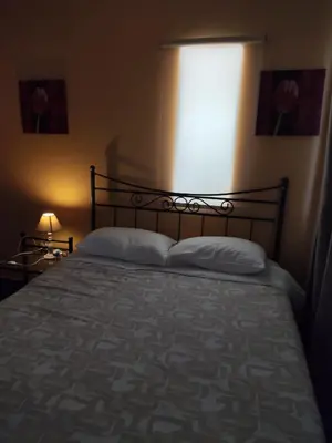 a bed in a bedroom with a light shining on it at Near Airport And metropolitan Artemis George Cozy Home in Artemida