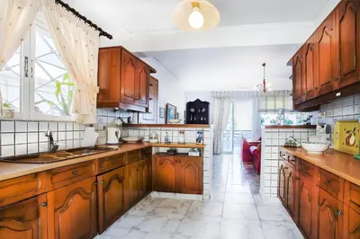 a kitchen with wooden cabinets and a large window at A gem next to the sea and close to the airport in Dhaskalión