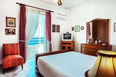 a bedroom with a bed and a television and a chair at A gem next to the sea and close to the airport in Dhaskalión