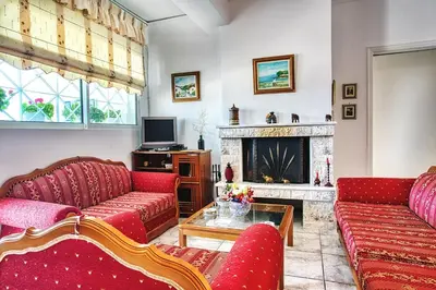 a living room with red couches and a fireplace at A gem next to the sea and close to the airport in Dhaskalión