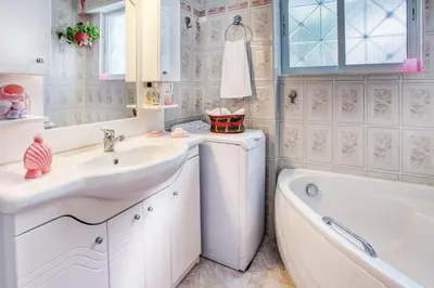 a white bathroom with a sink and a bath tub and a tubermott at A gem next to the sea and close to the airport in Dhaskalión