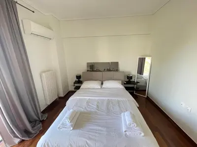 a white bedroom with a large bed in it at Kleio - Spacious apartment in Glyfada in Athens