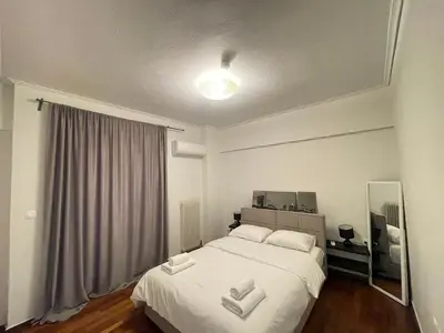 a bedroom with a large white bed and a mirror at Kleio - Spacious apartment in Glyfada in Athens