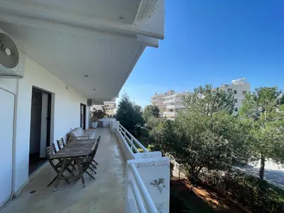 a balcony of a house with a wooden table and chairs at Kleio - Spacious apartment in Glyfada in Athens