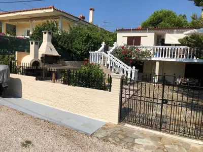 a house with a gate and a house with a fireplace at Your Holiday House in Porto Rafti