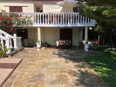 a house with a balcony and a patio with a table at Your Holiday House in Porto Rafti