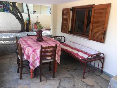 a table and chairs with a table and a bench at Your Holiday House in Porto Rafti