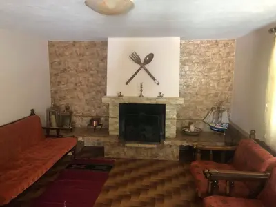 a living room with a fireplace with a clock on the wall at Your Holiday House in Porto Rafti