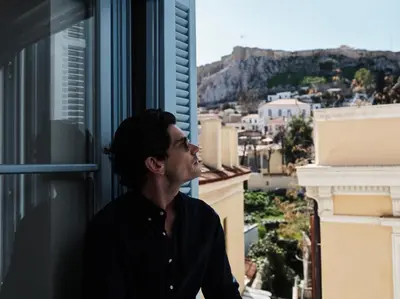 a man looking out the window of a building at A77 Suites, Small Luxury Hotels of the World in Athens