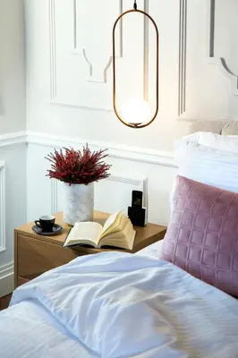 a bed with a table with a book and a lamp at A77 Suites, Small Luxury Hotels of the World in Athens
