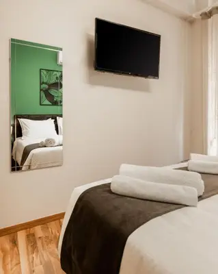 a bedroom with two beds and a tv on the wall at Monastiraki Urban Apartments in Athens