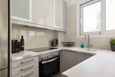 a white kitchen with a stove and a sink at Urban 2BD Apartment in Koukaki by UPSTREET in Athens