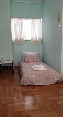 a bedroom with a bed with pink sheets and a window at Koukaki apartment near Acropolis in Athens