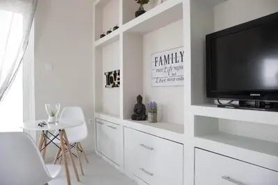a white living room with a tv and white cabinets at Breathtaking view penthouse at the heart of Thiseio, VP homes in Athens