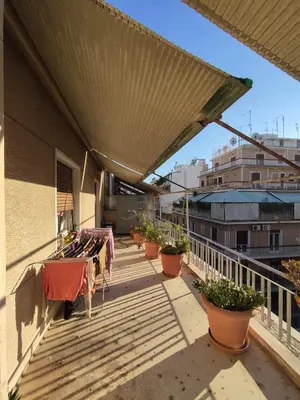 a balcony with tables and potted plants on a building at Zizi room in Athens