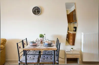 a dining room table with chairs and a clock on the wall at Charming Apartment near Athens Center and the Sea in Athens
