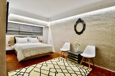 a bedroom with a bed and two chairs and a mirror at Kolonaki Spacious 1 Bd Apt with Outdoor Patio in Athens