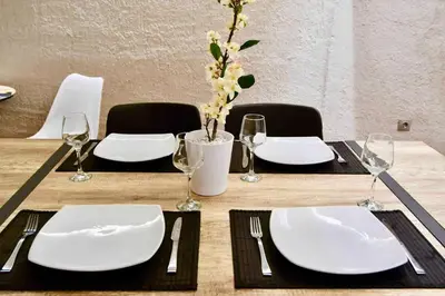 a wooden table with white plates and forks and napkins at Kolonaki Spacious 1 Bd Apt with Outdoor Patio in Athens