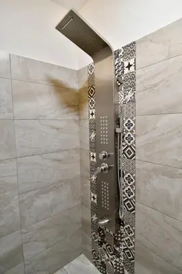 a shower in a bathroom with a tile wall at Kolonaki Spacious 1 Bd Apt with Outdoor Patio in Athens