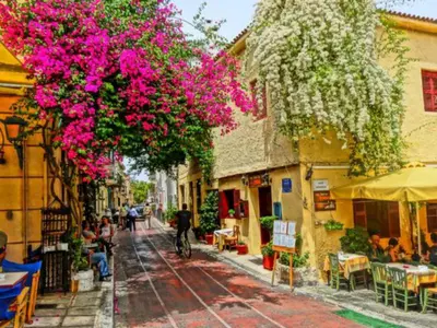 a street with pink flowers hanging from buildings at Αnna's Home 2 .Holidays in beautiful Athens in Athens